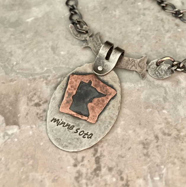 Handmade pierced metal pendant with cutout design created using jewelry piercing techniques