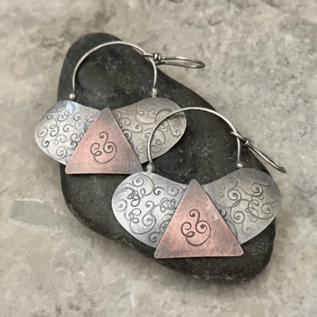 Handmade mixed metal earrings featuring textured silver ovals and copper triangle accents