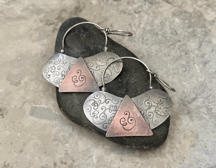Handmade mixed metal earrings featuring textured silver ovals and copper triangle accents
